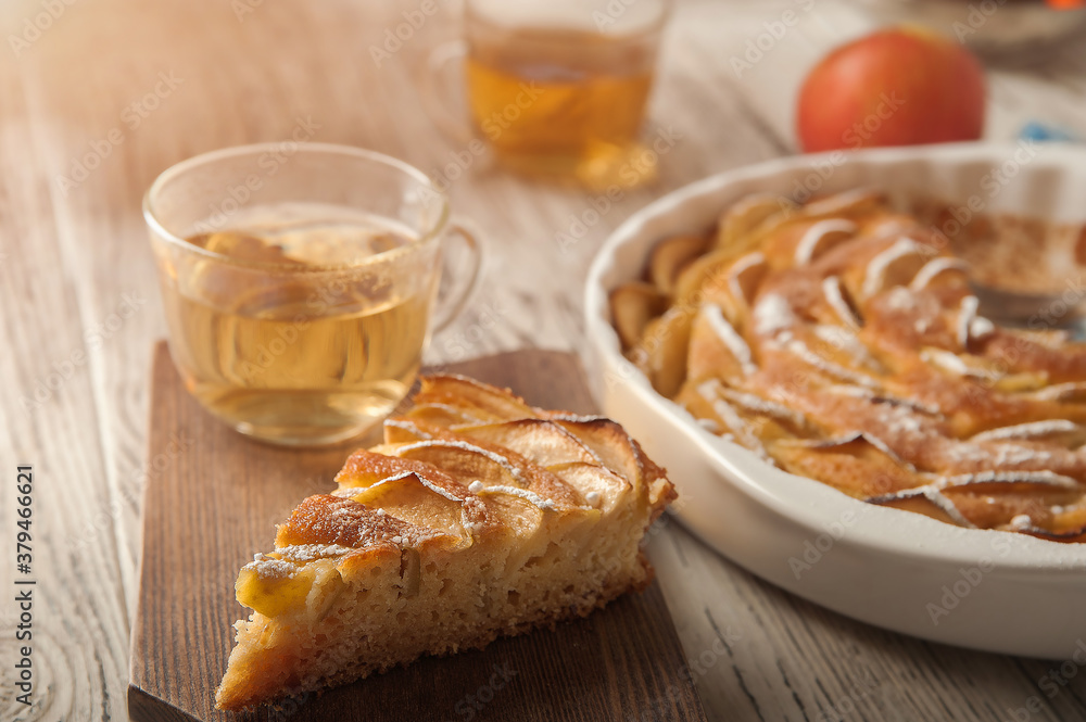 Homemade apple pie on a white wooden background near the window close-up and copy space. Charlotte in the morning on the table. Homemade apple pie on a white wooden background near the window close-up and copy space. Charlotte in the morning on the table.