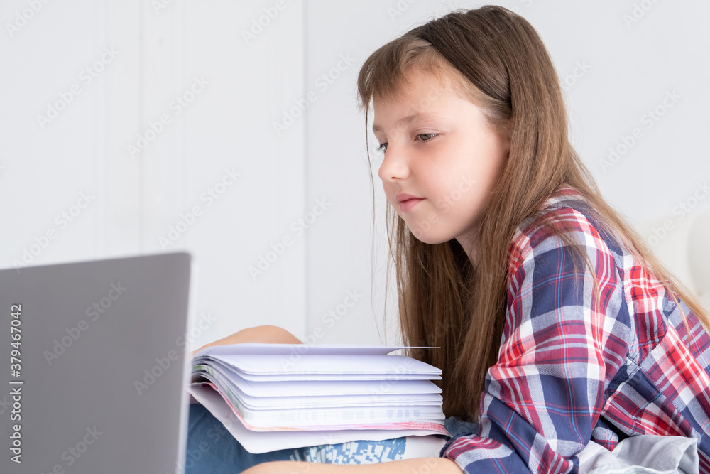Distance learning online education. Schoolgirl studying at home with digital laptop notebook and doing school homework lying on bed at home. Distance learning online education. Schoolgirl studying at home with digital laptop notebook and doing school homework lying on bed at home.