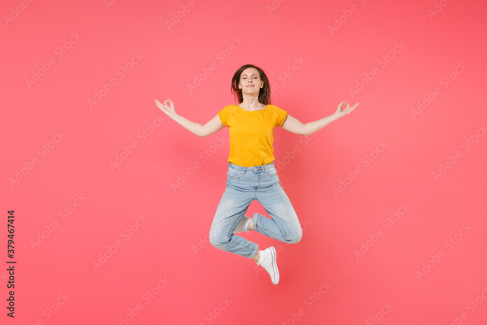 Full length portrait of young brunette woman 20s in yellow casual t-shirt posing jumping hold hands in yoga gesture, relaxing meditating, trying to calm down isolated on pink color background studio. Full length portrait of young brunette woman 20s in yellow casual t-shirt posing jumping hold hands in yoga gesture, relaxing meditating, trying to calm down isolated on pink color background studio.