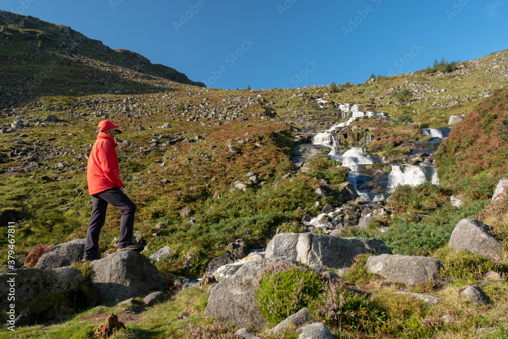 Tourist standing on the rock watching waterfall in Wicklow National Park
