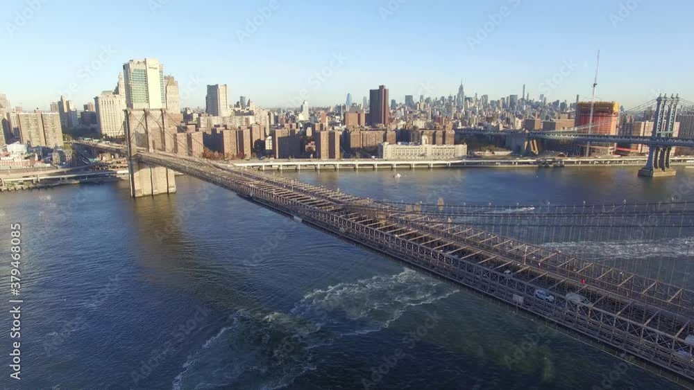 Acercamiento aéreo al Puente de Brooklyn, con muchos autos circulando, con el skyline de Manhattan como fondo al amanecer. Acercamiento aéreo al Puente de Brooklyn, con muchos autos circulando, con el skyline de Manhattan como fondo al amanecer.