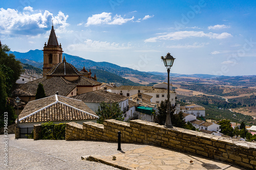 church in village with street lamp, blue sky and mountains in background