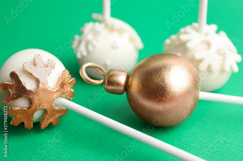 Delicious Christmas themed cake pops on green background, closeup