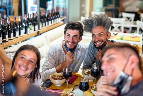 friends of different ethnicities pose at the Japanese restaurant for a selfie, focus on the black man, celebrations for the end of the lockdown and use of masks for the prevention