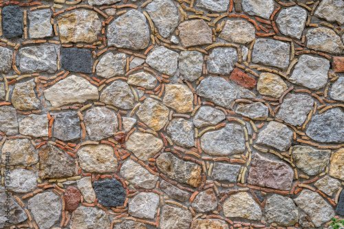 Mauer aus Natursteinen mit Resten von Dachziegeln in den Fugen als besonderer Hingucker