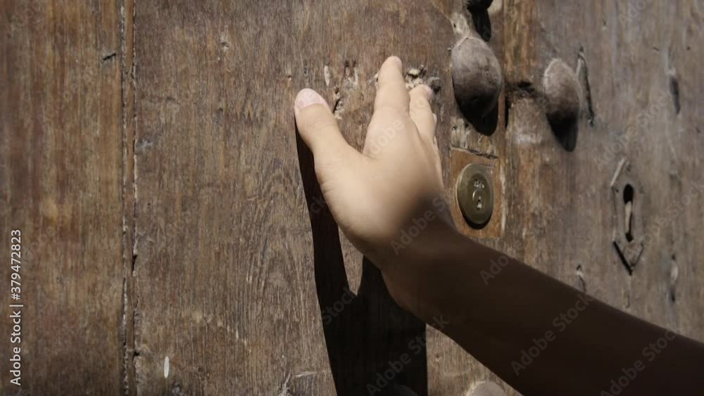 Mano de mujer blanca joven acariciando una puerta de madera antigua HD