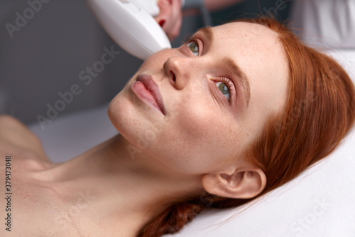 attractive woman receiving a non-surgical rejuvenation procedure, RF face lifting with the use of electric device equipment. hardware facial massage
