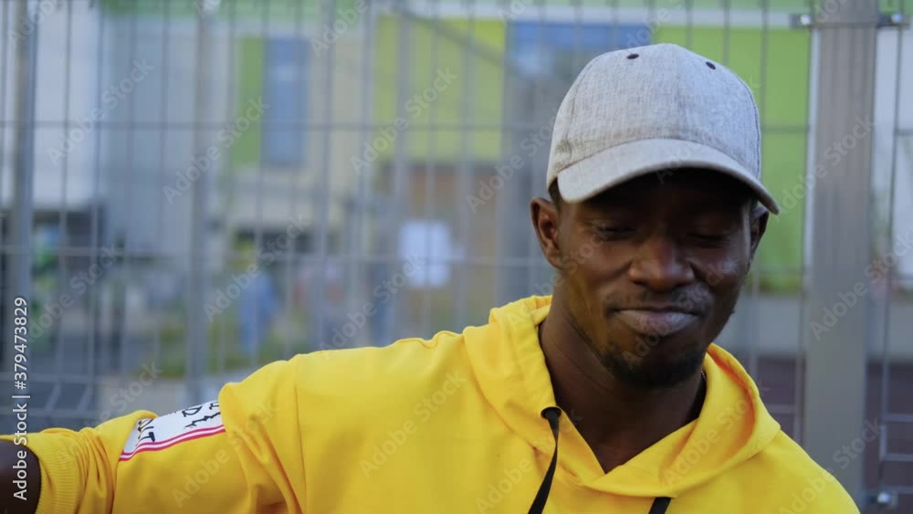 Black guy in yellow hoodie and grey cap dancing hip hop. A man is dancing in the street. Dance in the courtyard Black guy in yellow hoodie and grey cap dancing hip hop. A man is dancing in the street. Dance in the courtyard