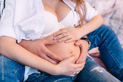 The man hugged his pregnant wife and put his hand on her stomach. Close-up