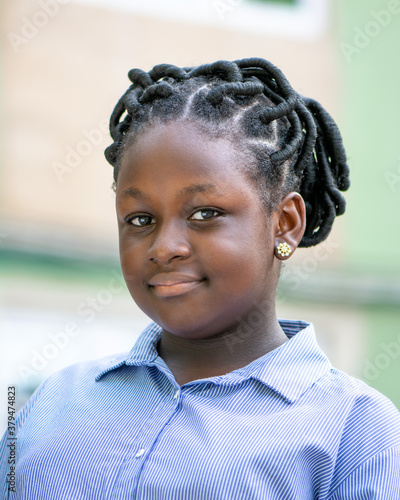 Portrait headshot of an African teenage girl outdoors with a traditional hairstyle.