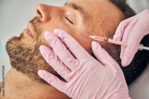 Serene young man receiving cosmetic facial injections