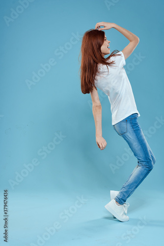 Pretty woman in white t-shirt blue jeans lifestyle in full growth studio blue background