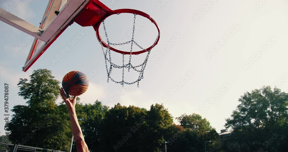 Male hand shot ball into basketball hoop. Ball scoring goal into basket