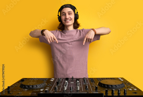 look, i will play on it. dj man with his equipment in studio. hipster man in casual t-shirt perform techno style club music. point fingers on set