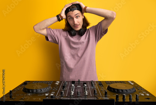surprised man hold head in shock standing in front of dj equipment, doesn't know how to play on it