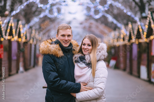Happy attractive couple at the Christmas market. Beautiful background of lights.