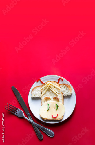 on a red background there is a children's breakfast a cheerful sandwich with cheese in the bull cow