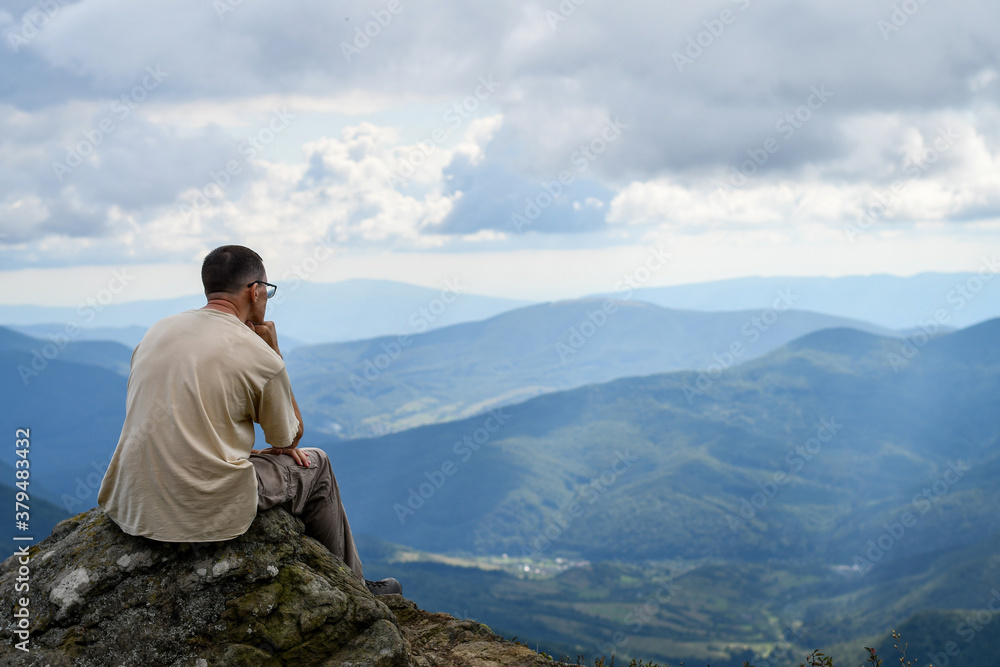 Back view of a man admiring amazing view on top of the mountain