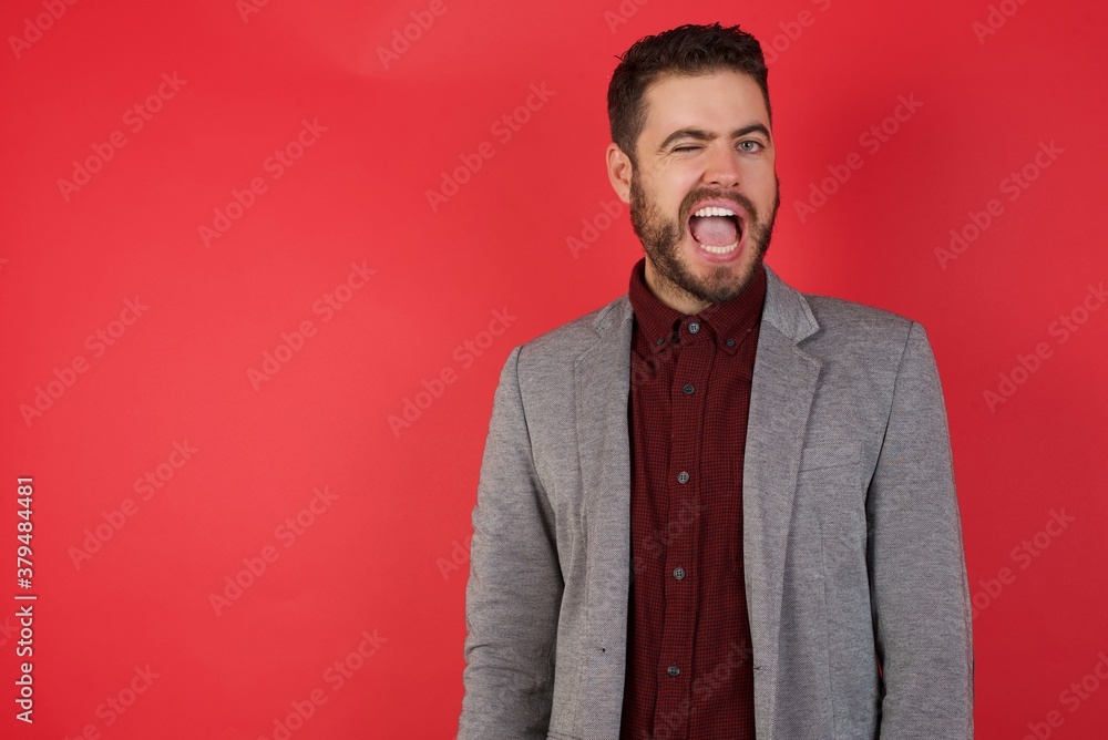 Young caucasian businessman wearing casual clothes standing over isolated red background winking looking at the camera with sexy expression, cheerful and happy face. Young caucasian businessman wearing casual clothes standing over isolated red background winking looking at the camera with sexy expression, cheerful and happy face.