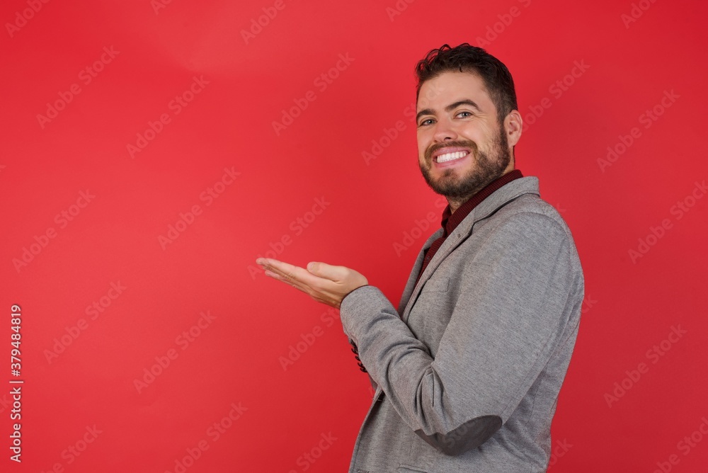 Young caucasian businessman wearing casual clothes standing over isolated red background pointing aside with hands open palms showing copy space, presenting advertisement smiling excited happy Young caucasian businessman wearing casual clothes standing over isolated red background pointing aside with hands open palms showing copy space, presenting advertisement smiling excited happy