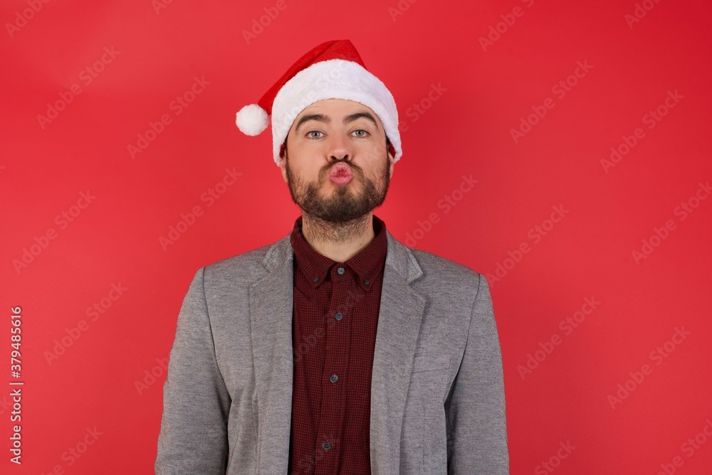 Shot of pleasant looking Young caucasian businessman wearing casual clothes standing over isolated red background pouts lips, looks at camera, has fun with girlfriend, Human facial expressions Shot of pleasant looking Young caucasian businessman wearing casual clothes standing over isolated red background pouts lips, looks at camera, has fun with girlfriend, Human facial expressions