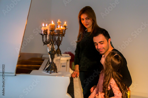 Happy Family Posing near Piano Decorated with Burining Candles photo