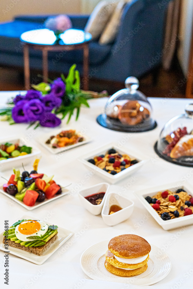 Tray plates with assorted breakfast meal on a bed in a hotel room