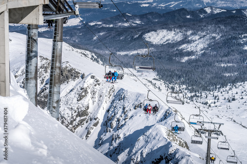 Skiers and snowboarders going up the ski slopes of Kasprowy Wierch on a ski lift. Winter holidays in High Tatra Mountains, Poland