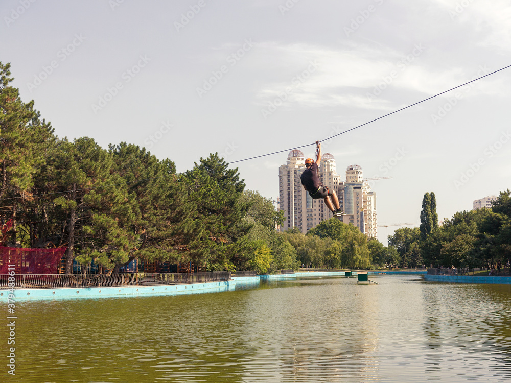 Odessa, Ukraine, July 29, 2018: lake in a city park on a sunny summer day. The guy on the rope over the pond at the city rides in the park.
