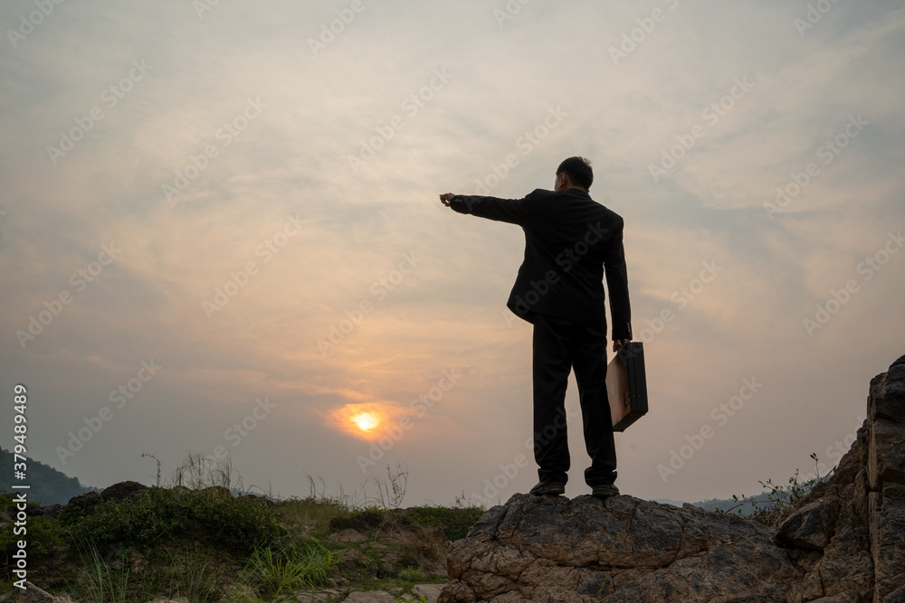 © visoot - Businessman standing on mountain at sunset background,Business success concept.