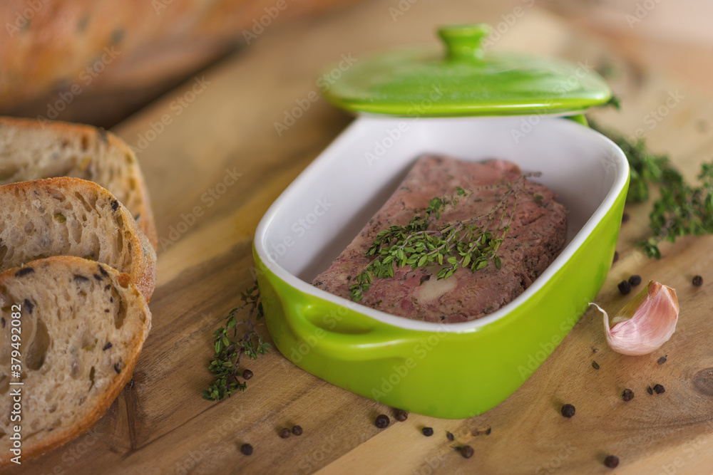 Almond pate with thyme in a green ceramic bowl, which lies on a wooden board next to slices of olive bread, a clove of garlic and pepper. Almond pate with thyme in a green ceramic bowl, which lies on a wooden board next to slices of olive bread, a clove of garlic and pepper.