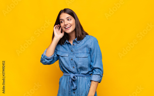 young pretty woman smiling, looking curiously to the side, trying to listen to gossip or overhearing a secret photo