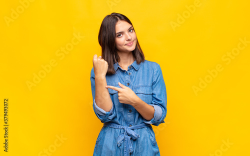 young pretty woman looking impatient and angry, pointing at watch, asking for punctuality, wants to be on time photo