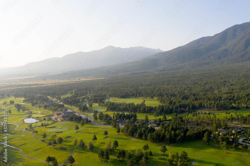 Aerial view from a drone. Stunning mountain views, hotels in the ski resort of Bansko, green golf courses in the morning at dawn. Travel and vacation concept