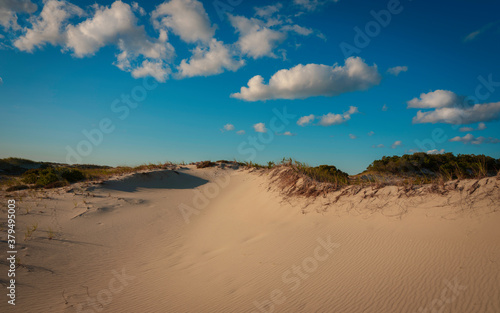 Cumulus clouds floating over the sand dunes. Abstract wilderness landscape. Smooth curving shapes of the sandhill on Cape Cod in Autumn.