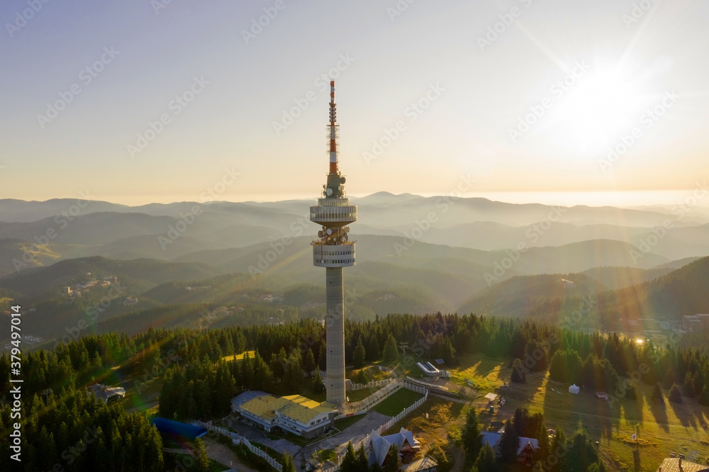 Telecommunication tower on top of the mountain in Pomporovo, Bulgaria. Aerial photo of a TV tower drone in the colorful rays of the setting sun on a mountain.