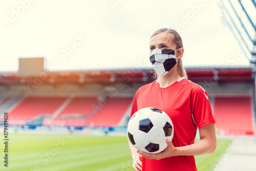 Woman football player wearing face mask in empty stadium © Kzenon