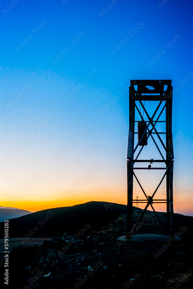 Silhouette of steel tower at sunrise, sunset, hills Silhouette of steel tower at sunrise, sunset, hills