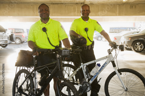 Fotografie Portrait of police officers with bicycles standing in parking lot