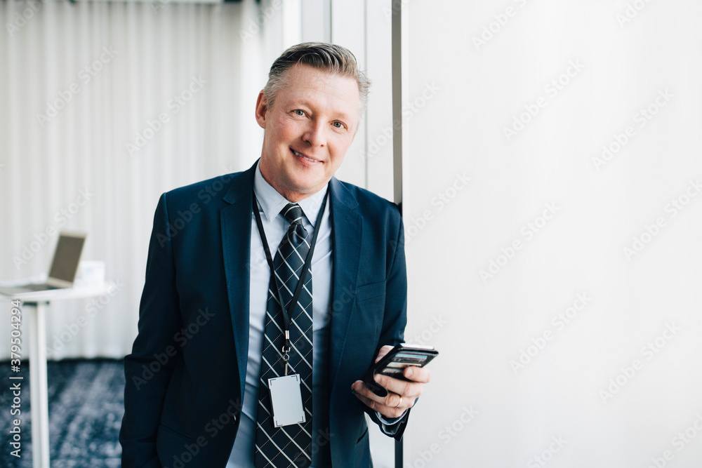 Portrait of smiling entrepreneur with mobile phone in office Portrait of smiling entrepreneur with mobile phone in office