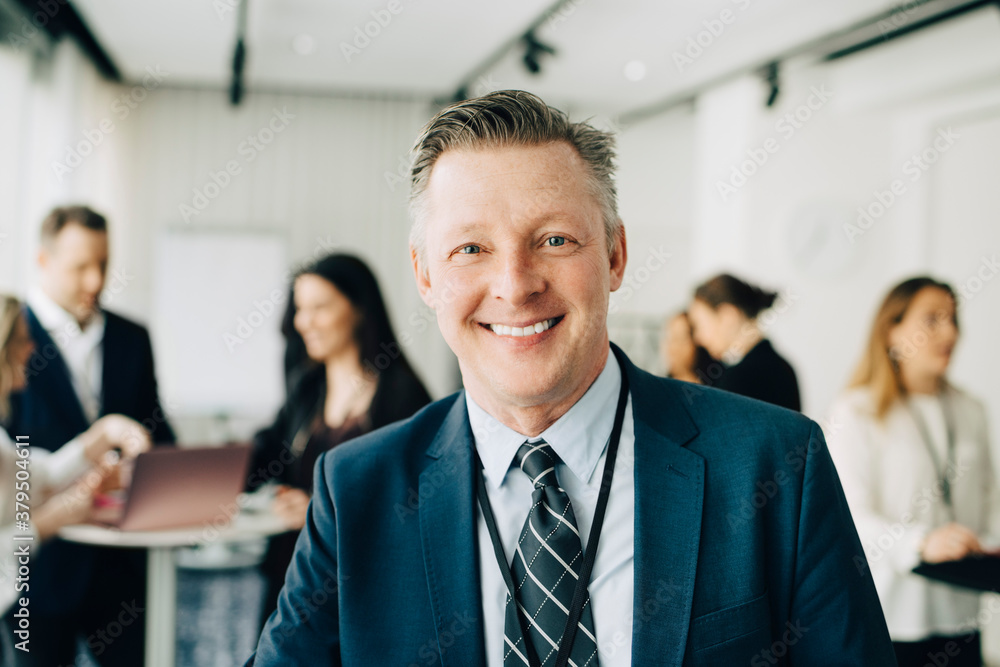 Portrait of happy businessman standing in office seminar Portrait of happy businessman standing in office seminar