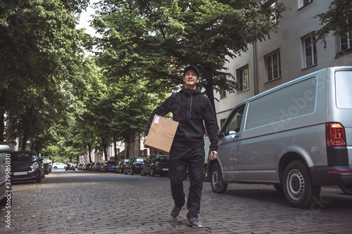 Confident delivery man with package walking on street in city photo