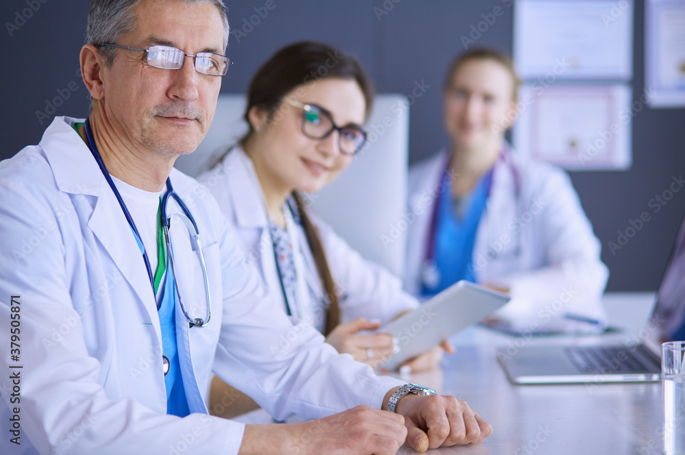 Serious medical team using a laptop in a bright office Serious medical team using a laptop in a bright office