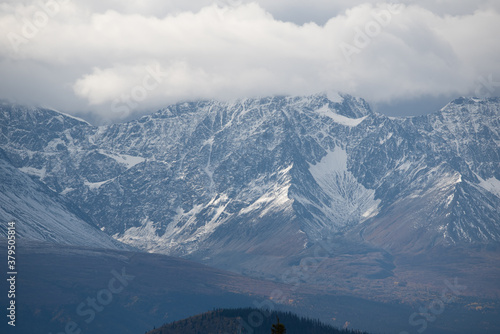 Mountain top shot of a moody, cloudy day with snow running down the mountains. Located in Haines Junction, Yukon Territory. 
