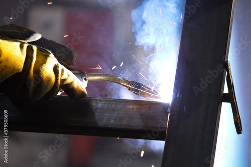 The welder is welding to structure steel material with gas metal arc welding process in the workshop. photo