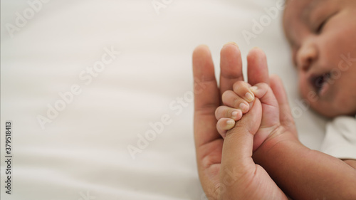 Fotografía african american new born baby hand holding mom finger on white bed