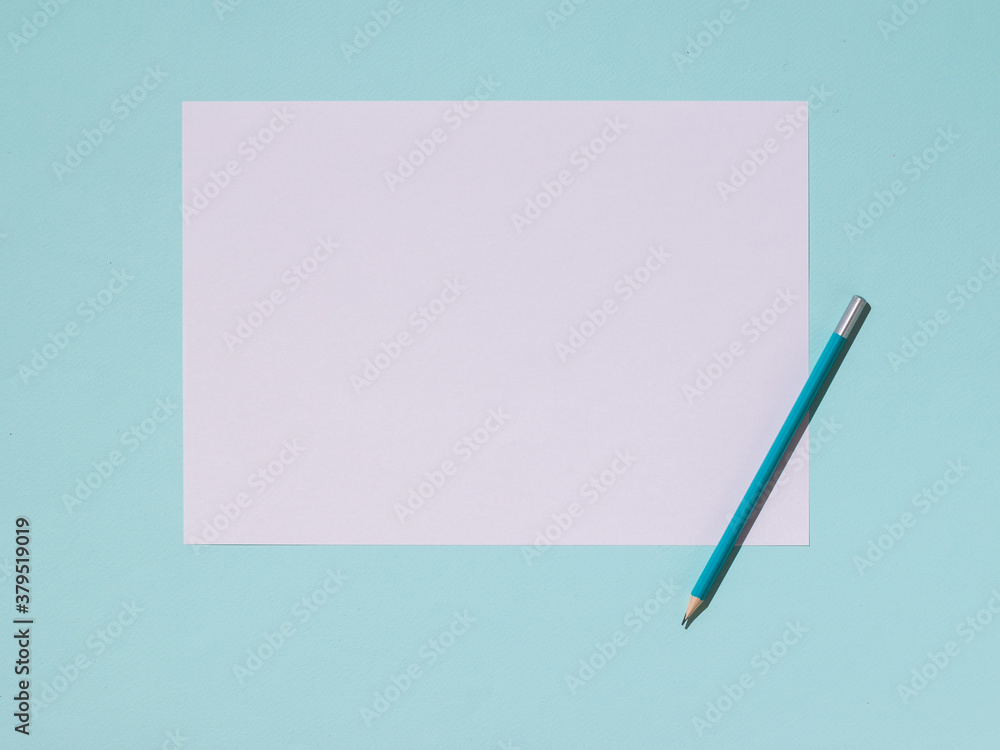 Graphite pencil and a white sheet of paper on a blue background. Graphite pencil and a white sheet of paper on a blue background.