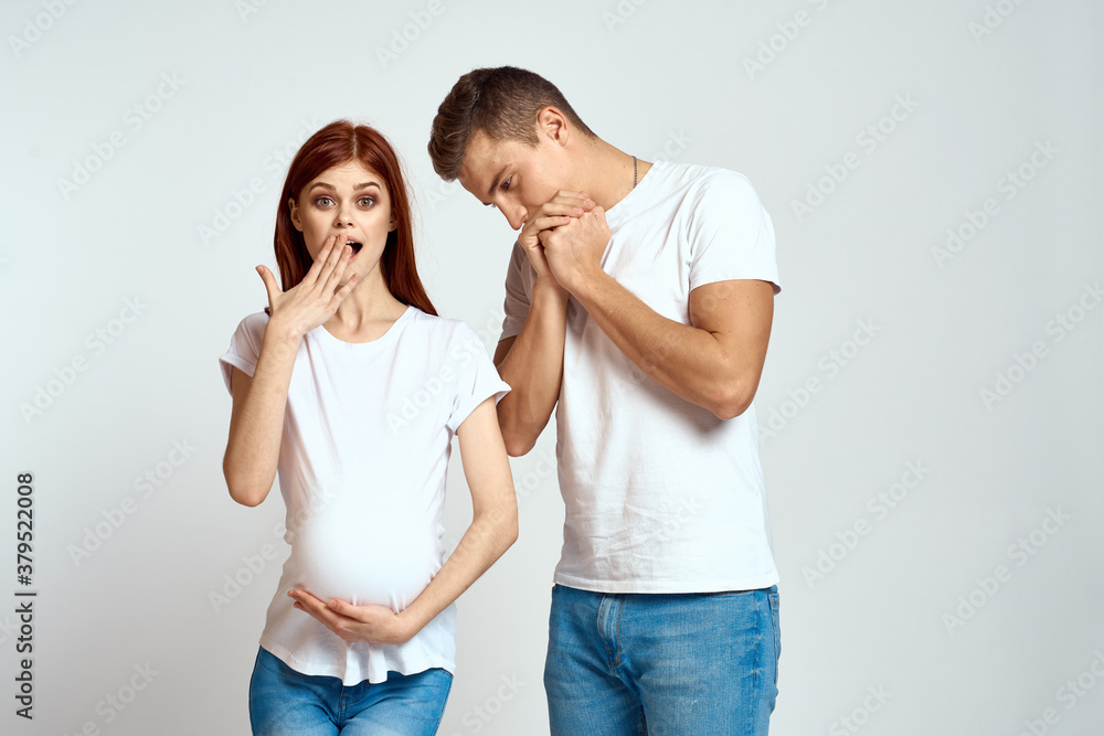 a pregnant woman and a young man are waiting for a baby on a light background emotions family love a pregnant woman and a young man are waiting for a baby on a light background emotions family love