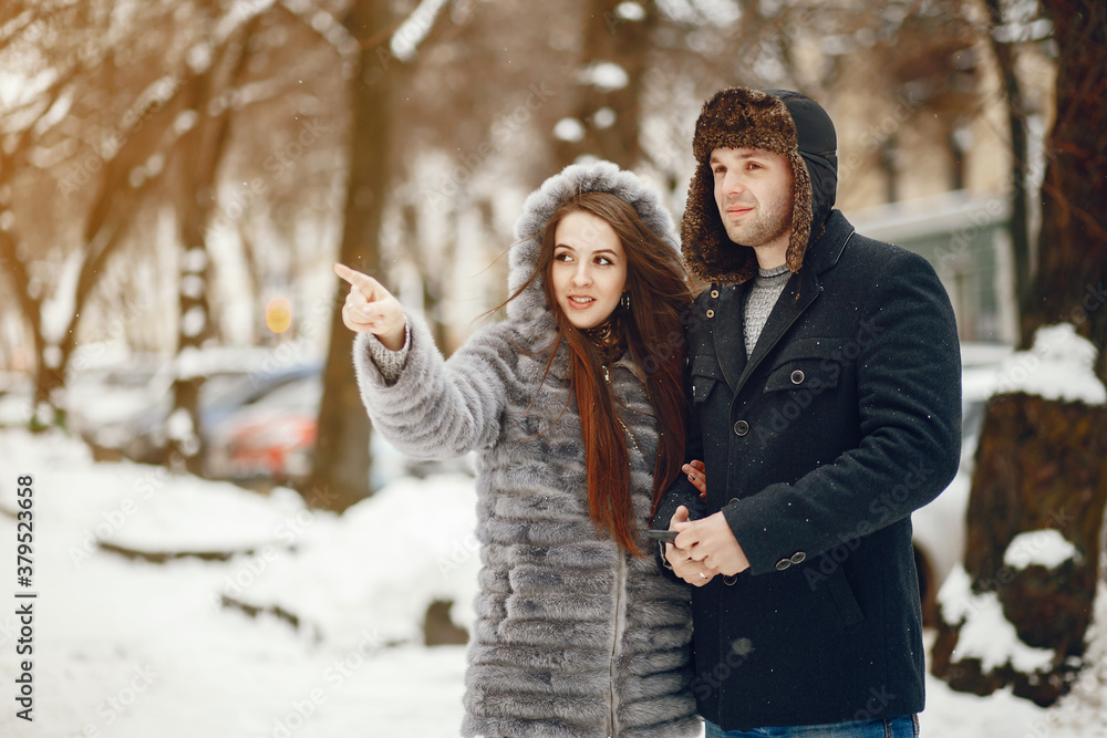 Obraz premium Cute couple walking in a winter city. Elegant woman in a gray fur coat