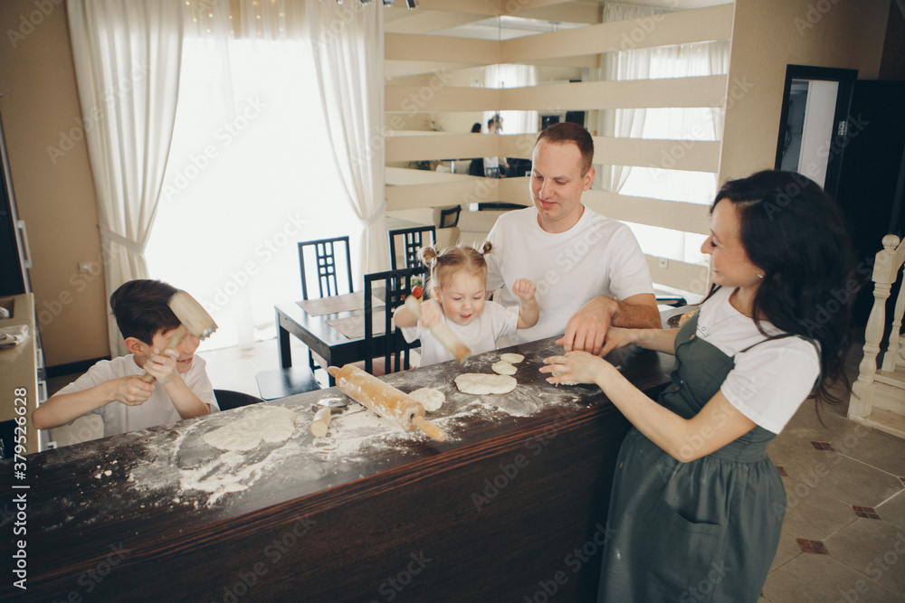 Obraz premium the family makes cakes. the children were covered in flour. dinner at the bakery. feast in the kitchen. mother's little helpers